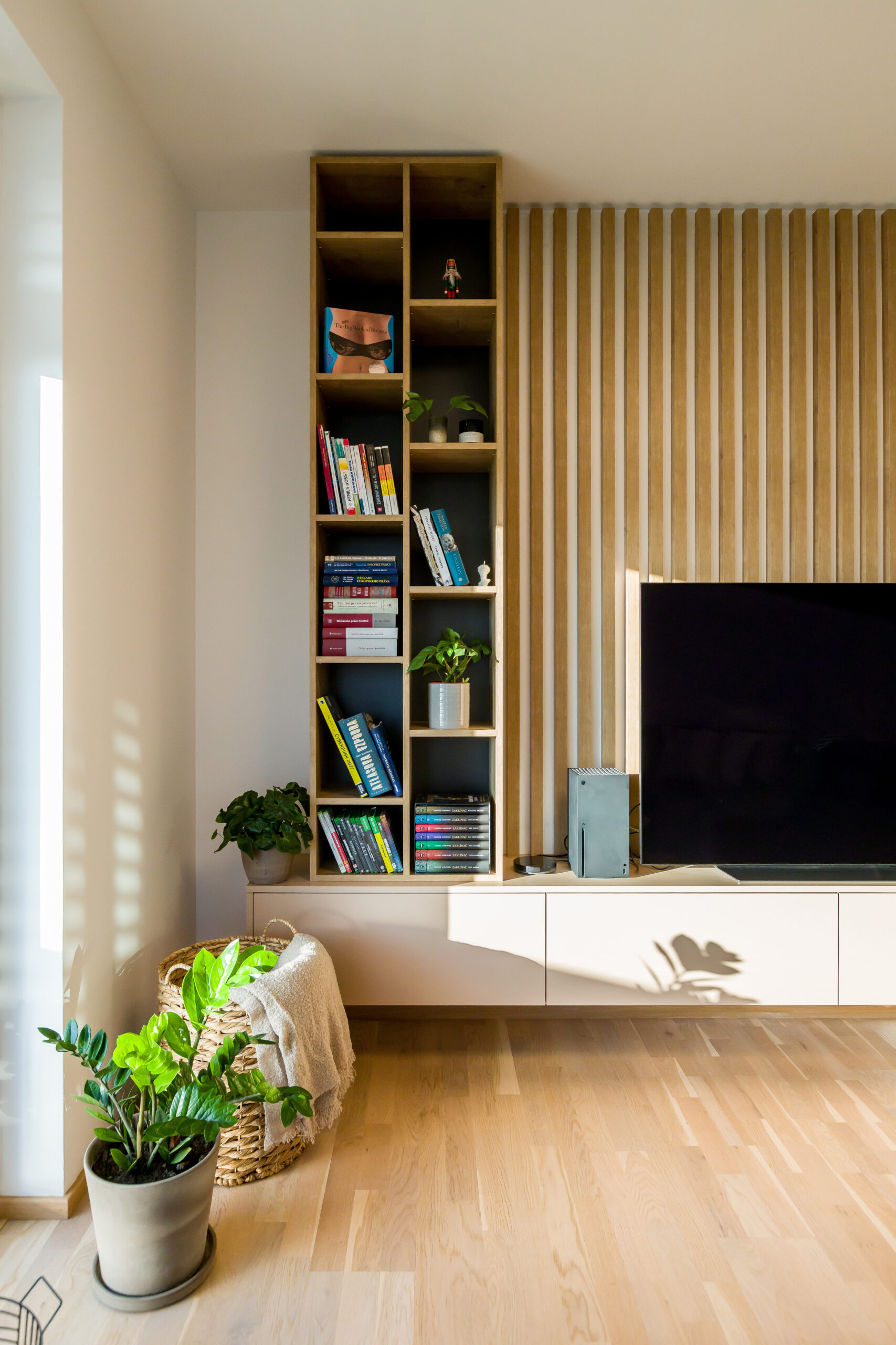 Detailná časť knižnice s televíznou stenou a dekoráciami v modernom interiéri, realizácia od INTTERIO Bratislava